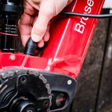 Eine Person schließt ein Ladekabel am Rahmen eines E-Bikes an.