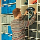 Ein Mann nimmt einen Fahrradhelm aus einem Regal.