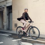 Eine Frau fährt auf einem Fahrrad durch eine Stadt.