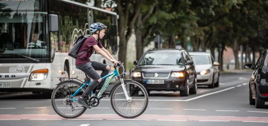 Ein Junge überquert auf einem Fahrrad eine Kreuzung.