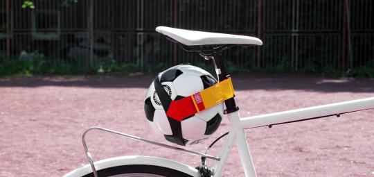 Ein Fußball unter dem Sattel eines Fahrrads befestigt.