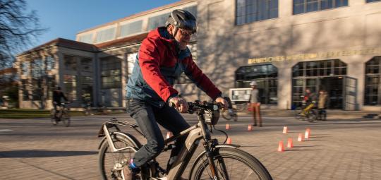Ein Mann fährt auf einem gepflasterten Platz ein E-Bike.