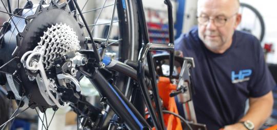 Ein Mechaniker arbeitet an einem Fahrrad oder Liegerad mit Hinterradmotor.