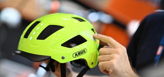 Eine Person präsentiert einen Fahrradhelm in Neongelb.