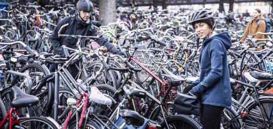 Zwei Personen mit Helmen stehen in einer großen Menge abgestellter Fahrräder.