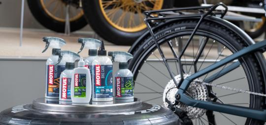 Mehrere Plastikflaschen mit Pflegemitteln vor einem Fahrrad.