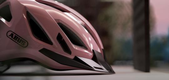 Ein rosa Fahrradhelm mit dem Logo der Firma Abus darauf, von der Seite betrachtet.