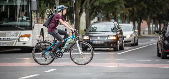 Ein Junge überquert auf einem Fahrrad eine Kreuzung.