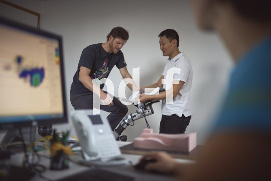 Ein Mann sitzt auf einem Ergometer. Ein zweiter Mann steht daneben und zeigt ihm etwas.