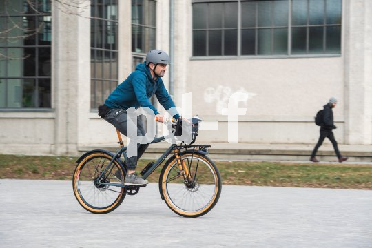 Ein Mann fährt auf einem Fahrrad vor einem Gebäude entlang.