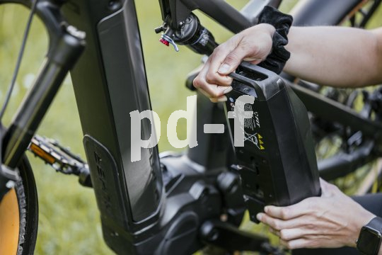 Eine Person hält einen Akku neben ein E-Bike.