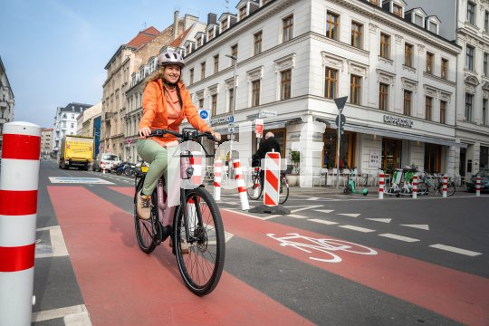 Eine Frau fährt auf einem E-Bike auf einer Radspur durch die Stadt.