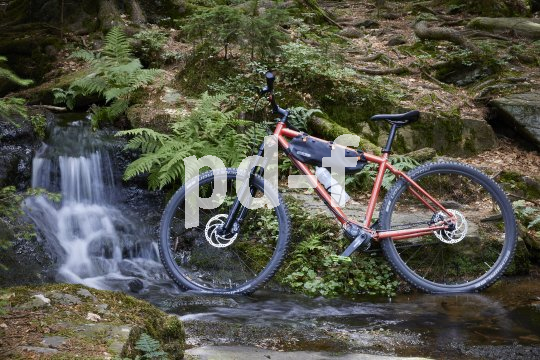 Mountainbike steht vor Wasserfall.