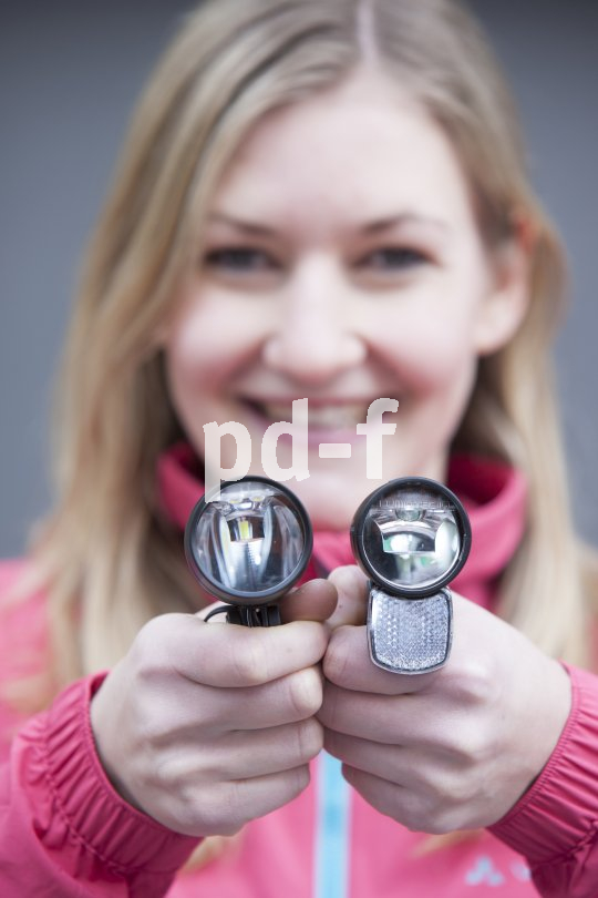 Eine Frau hält zwei Fahrradscheinwerfer vor sich.