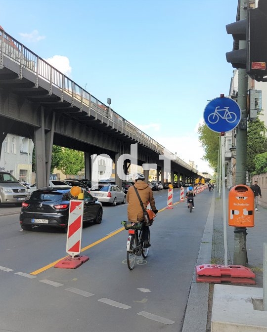 Eine Person fährt mit einem Fahrrad auf einem Bereich einer Straße, der mit Leitbaken von Autospuren getrennt ist.