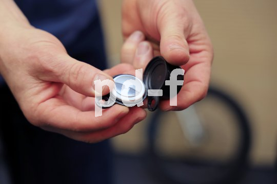 Eine Person öffnet eine Fahrradklingel, um ein Apple Airtag darin zu zeigen.