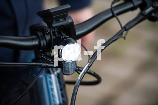 Die Bildunterschrift wird in Bälde eingefügt. Sie können uns aber gern auch per E-Mail oder Telefon kontaktieren, wir helfen gerne weiter. Ein am Lenker eines Fahrrades montierter Scheinwerfer mit Reflektor.