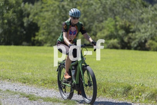 Eine Frau fährt mit einem Fahrrad auf einen Feldweg.
