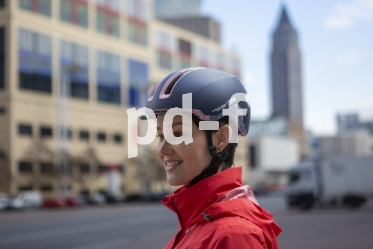 Moderne Fahrradhelme, wie der "Hud-Y" von Abus, überzeugen bei der Sicherheit und der Optik. Frau mit Fahrradhelm in Stadt