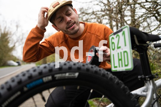 Mann versucht Kennzeichen an Kinderrad anzubringen.