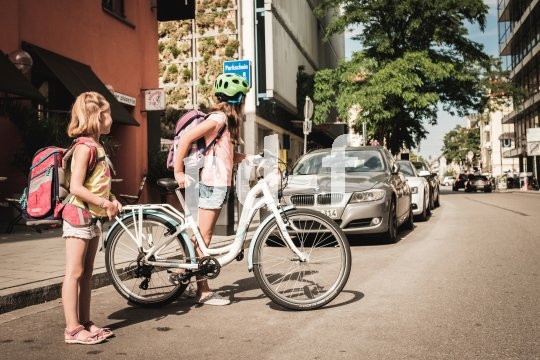 Vollwertig ausgestattete Fahrräder für Kinder werden derzeit immer leichter, wie Puky mit dem 24-Zöller "Skyride AL 24-8" zeigt. Ein Mädchen mit und eins ohne Fahrrad stehen am Straßenrand und schauen nach Autos, bevor sie die Straße überqueren.