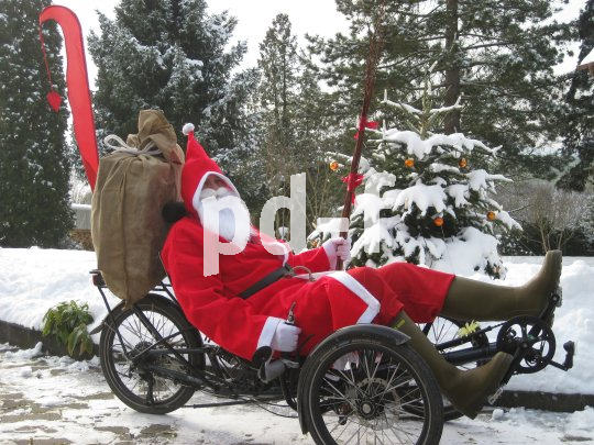 Eine als Weihnachtsmann verkleidete Person auf einem Liegedreirad.