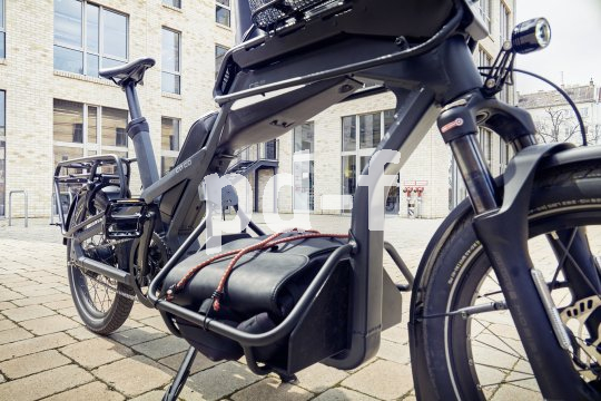 Cargobike mit Ladung parkt vor Gebäude.