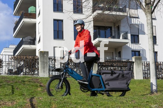 Frau fährt Lastenrad vor Wohnhaus