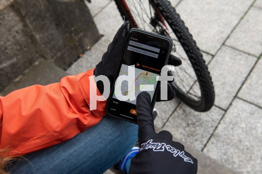 Ein Smartphone mit einer Navigations-App in der Hand einer Person mit Handschuhen.