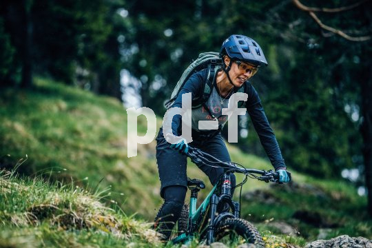 Frau fährt mit Mountainbike über Wiese.