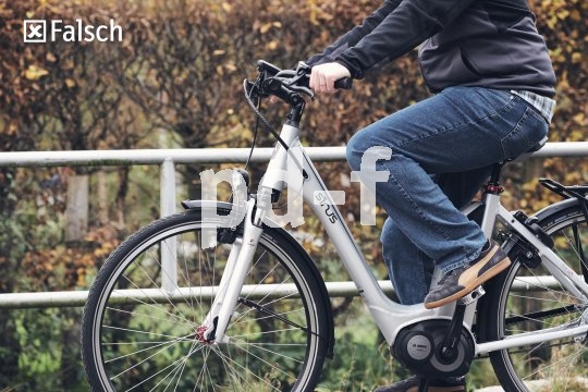 Eine Person sitzt mit angewinkelten Knien auf einem E-Bike.