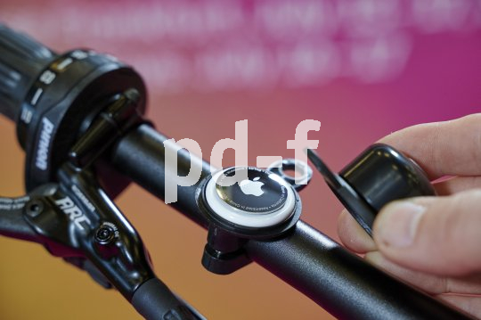 Ein Apple Airtag im Inneren einer demontierten Fahrradklingel an einem Lenker.