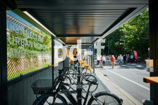 In einem einseitig offenen Metallcontainer stehen mehrere Fahrräder an Haltevorrichtungen.