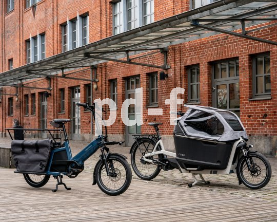 Zwei Lastenräder vor einem Gebäude mit Ziegelfassade.
