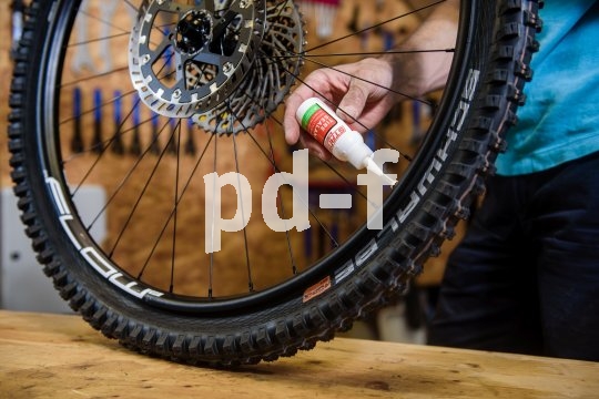 Über die spitze Kappe der kleinen Flasche wird die Dichtmilch durch den offenen Ventilschaft in den Reifen eingefüllt.