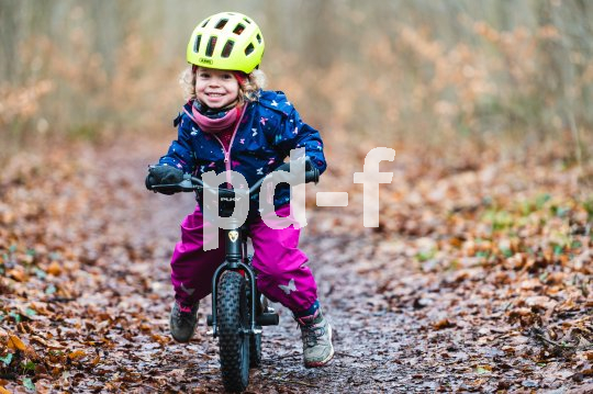Laufräder sind für viele Kinder der Einstieg in den Fahrradbereich. Kind fährt mit Laufrad im Wald