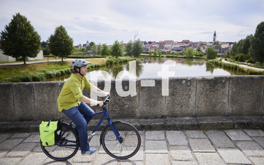 Mann fährt mit Fahrrad über historische Brücke.
