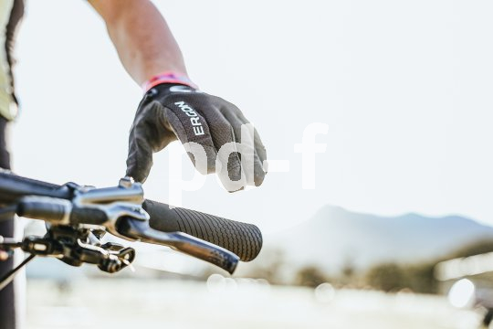 Die linke Hand einer Person über dem Lenkergriff eines Fahrrades.