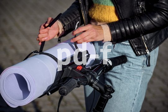 Frau fixiert Sportmatte auf Gepäckträger