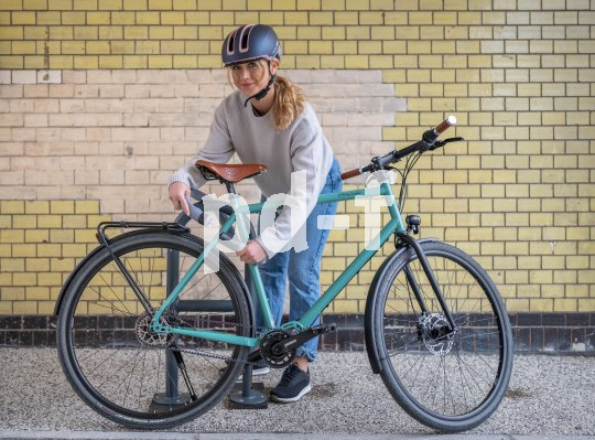 Wichtig als Schutz gegen Diebstahl ist das Anschließen des Fahrrads an einen festen Gegenstand. Frau schließt Fahrrad an