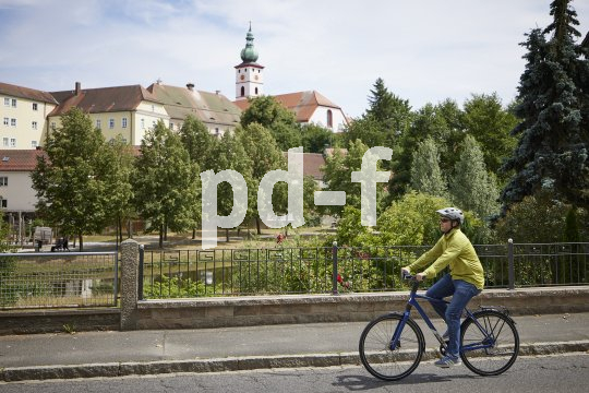 Mann fährt mit Fahrrad vor Kirche