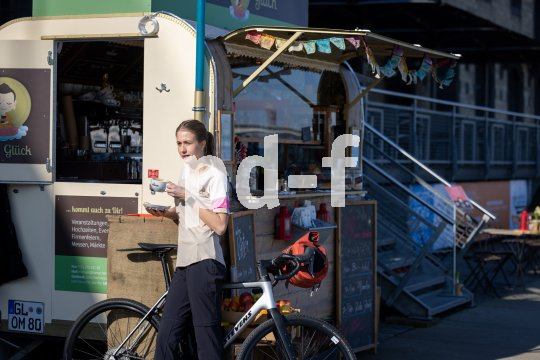 Frau steht mit Tasse Kaffee vor Kiosk