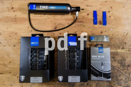 Die neben den Laufrädern benötigten Teile: Reifen, Dichtmilch, Tubeless-Ventile, Reifenheber, Spezialpumpe oder Hochdruckreservoir (gegen den Uhrzeigersinn).