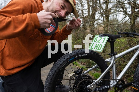 Mann versucht Kennzeichen an Kinderrad anzubringen.