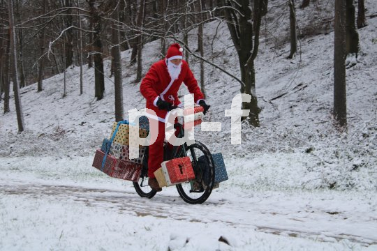 Weihnachtsmann fährt mit Fahrrad durch Winterwald