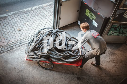 Ein Mann schiebt einen Fahrradanhänger mit alten Fahrradreifen aus einem Tor heraus.