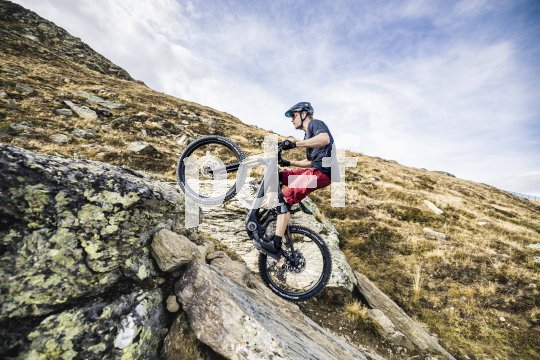 Mann fährt steile Rampen in den Bergen mit E-Mountainbike hoch