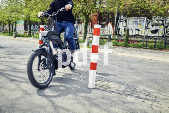 Mensch manövriert Cargobike durch Absperrungen.