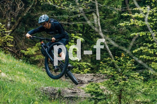 Mann springt mit Mountainbike über Hindernis. 