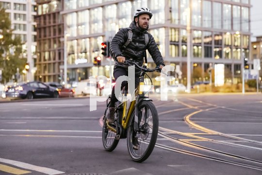 Ein Mann fährt auf einem E-Bike über eine Straßenkreuzung mit Straßenbahnschienen.